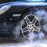 Close-up of a luxury car wheel with steam and water droplets, showcasing power and style.